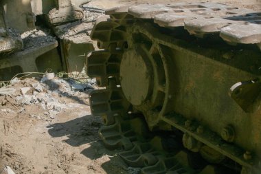 Bir yıkım alanındaki engebeli, çamurlu kazı alanının yakın çekimi. Arka planda enkaz ve beton parçaları görülüyor.