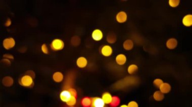 Sıcak sarı, turuncu ve kırmızı Bokeh ışıkları siyah bir gece arkaplanına karşı parıldıyor, romantik bir havayı çağrıştırıyor..