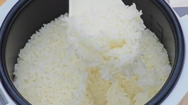 Bir el, pilav pişiricisinden sıcak, kokulu pilav kepçesi.