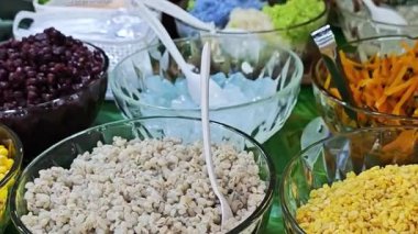  Taze hindistan cevizi sütlü tatlı, üzerinde mısır, kırmızı fasulye ve çeşitli malzemelerle doğal hindistan cevizi kabuğu ile servis edilir, canlı Tayland sokak yemekleri sergilenir..