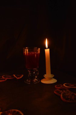Bir grup yanan mum ve siyah arka planda sıcak şarap..