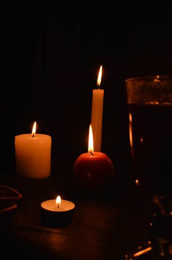 Bir grup yanan mum ve siyah arka planda sıcak şarap..
