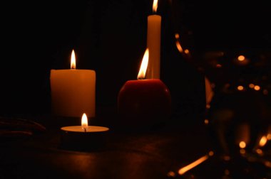 Bir grup yanan mum ve siyah arka planda sıcak şarap..