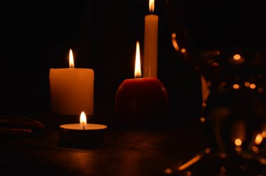Bir grup yanan mum ve siyah arka planda sıcak şarap..