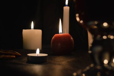 Bir grup yanan mum ve siyah arka planda sıcak şarap..