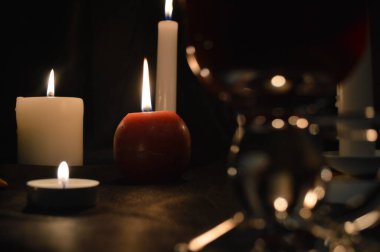 Bir grup yanan mum ve siyah arka planda sıcak şarap..