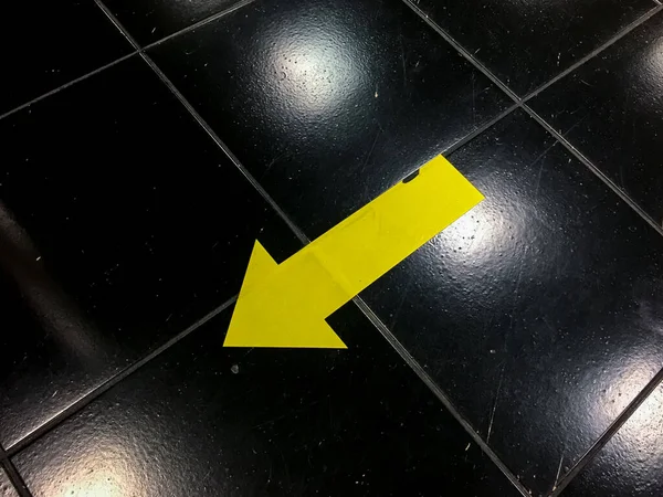 Yellow arrow indicating the direction of movement on the floor. Black tile with scratched surface