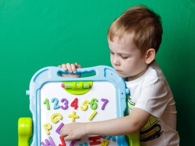 Bir çocuk rakamları ve harfleri tahtada öğrenir.