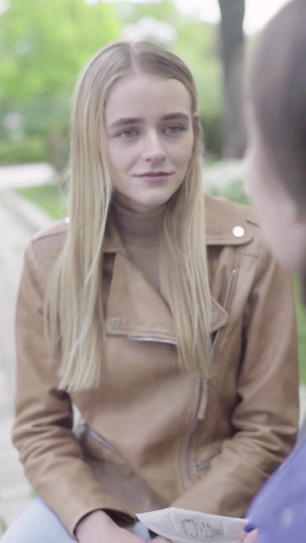 Vídeo vertical de uma jovem magricela no parque. Menina falando com alguém — Vídeo de Stock
