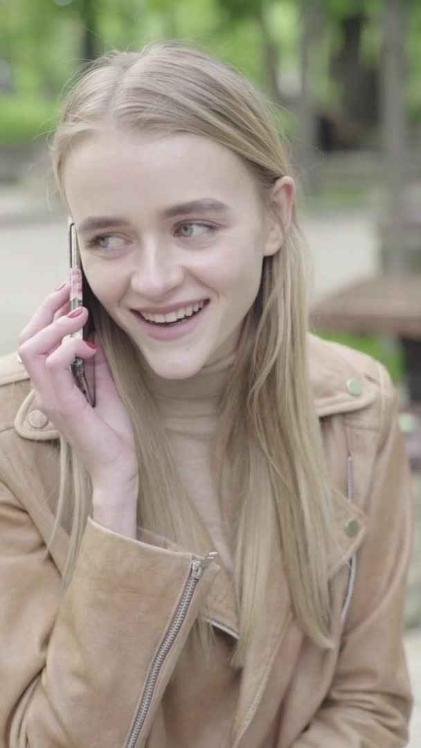 公園の若い痩せた女の子の垂直ビデオ。携帯電話を持つ少女. — ストック動画
