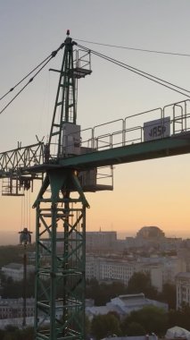 Dikey video - Şafakta şehirde inşaat vinci. Kyiv, Ukrayna.