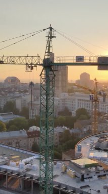 Dikey video - Şafakta şehirde inşaat vinci. Kyiv, Ukrayna.