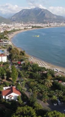 Dikey video Alanya, Türkiye - deniz kıyısında bir tatil köyü. Hava görünümü