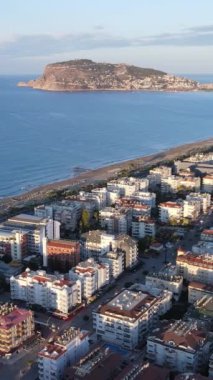 Dikey video Alanya, Türkiye - deniz kıyısında bir tatil köyü. Hava görünümü
