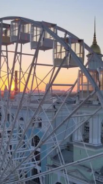 Ukrayna, Kyiv 'de sabah gün doğumunda dönme dolap. Dikey video