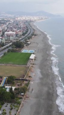 Dikey video Alanya, Türkiye - deniz kıyısında bir tatil köyü. Hava görünümü