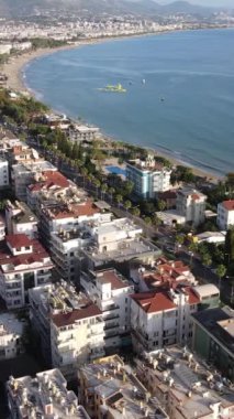 Dikey video Alanya, Türkiye - deniz kıyısında bir tatil köyü. Hava görünümü