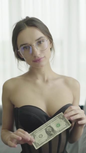 Vertikal video. Flicka i sexiga underkläder. Sakta i backarna. Flickan håller en dollar i händerna och lägger den i behån. — Stockvideo