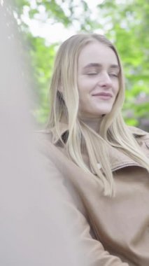 Parktaki genç, sıska bir kızın dikey videosu. Kız biriyle konuşuyor.