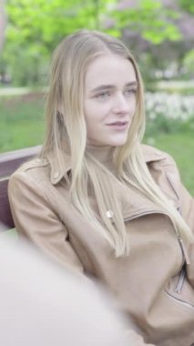 Parktaki genç, sıska bir kızın dikey videosu. Kız biriyle konuşuyor.