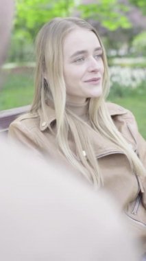 Parktaki genç, sıska bir kızın dikey videosu. Kız biriyle konuşuyor.