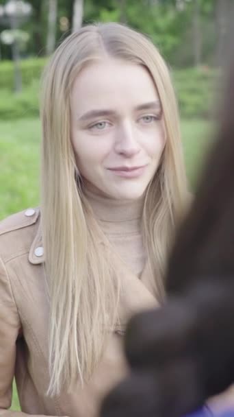 Vertical video of a young skinny girl in the park. Girl talking with someone — Stock Video