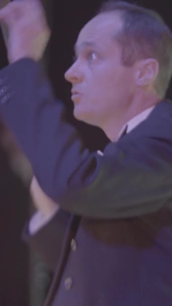 A male conductor conducts on stage. Vertical video — Stock Video