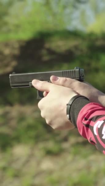 Közelkép egy pisztolyról. Függőleges videó — Stock videók