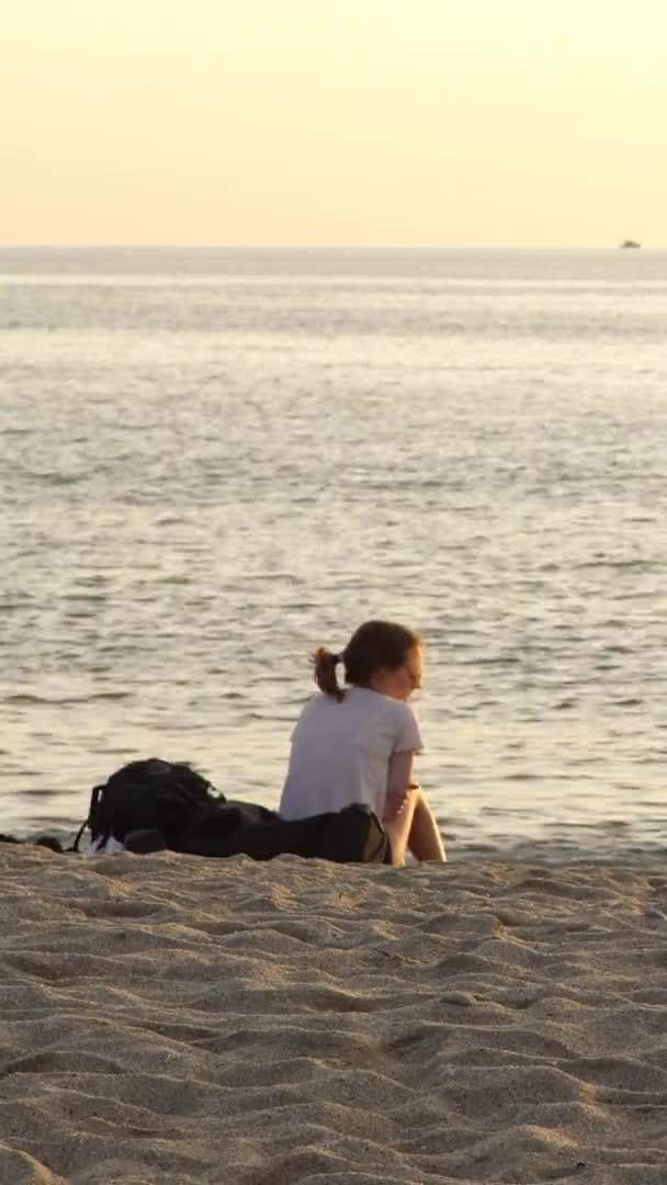 Fille assise au bord de la mer sur le sable Vidéo verticale — Video
