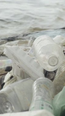 Deniz kıyısındaki dikey videoda plastik çöpler