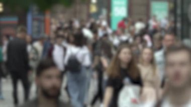 Büyük şehir hayatı: insanların siluetleri kalabalık içinde yürüyor, ağır çekimde.