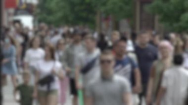 Büyük şehir hayatı: insanların siluetleri kalabalık içinde yürüyor, ağır çekimde.