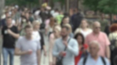 Büyük şehir hayatı: insanların siluetleri kalabalık içinde yürüyor, ağır çekimde.