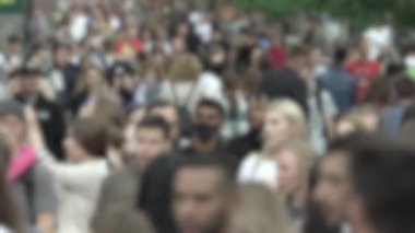 Büyük şehir hayatı: insanların siluetleri kalabalık içinde yürüyor, ağır çekimde.