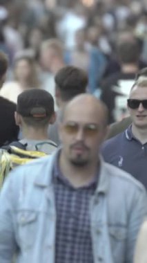 Vertical video of pedestrians walking along a city street