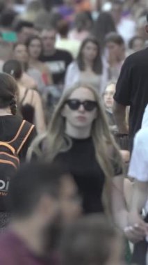Vertical video of pedestrians walking along a city street