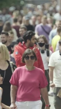 Vertical video of pedestrians walking along a city street