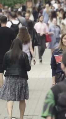 Vertical video of pedestrians walking along a city street