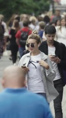 Vertical video of pedestrians walking along a city street