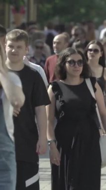 Vertical video of pedestrians walking along a city street