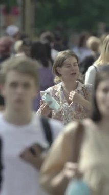 Vertical video of pedestrians walking along a city street