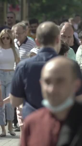 Vertical video of pedestrians walking along a city street — Stockvideo