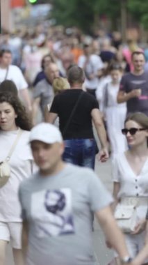 Şehir caddesi boyunca kalabalık içinde yürüyen bir sürü insanın dikey videosu.