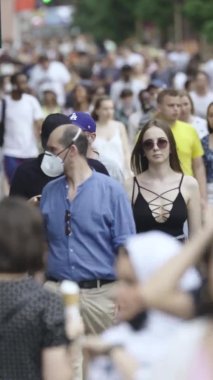 Şehir caddesi boyunca kalabalık içinde yürüyen bir sürü insanın dikey videosu.