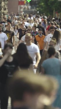 Şehir caddesi boyunca kalabalık içinde yürüyen bir sürü insanın dikey videosu.