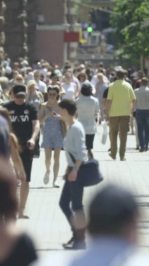 Şehir caddesi boyunca kalabalık içinde yürüyen bir sürü insanın dikey videosu.