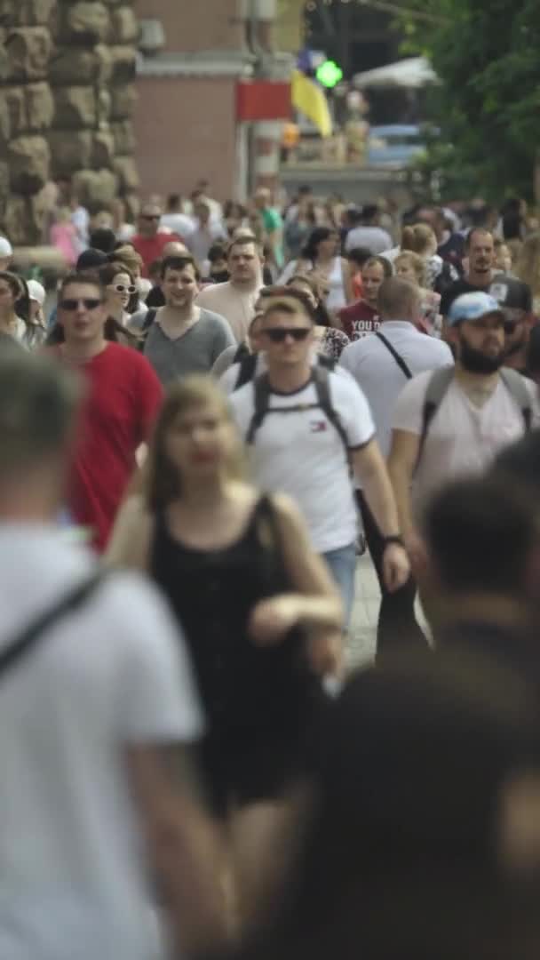 Vídeo vertical de muitas pessoas andando em uma multidão ao longo de uma rua da cidade — Vídeo de Stock