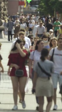 Şehir caddesi boyunca kalabalık içinde yürüyen bir sürü insanın dikey videosu.