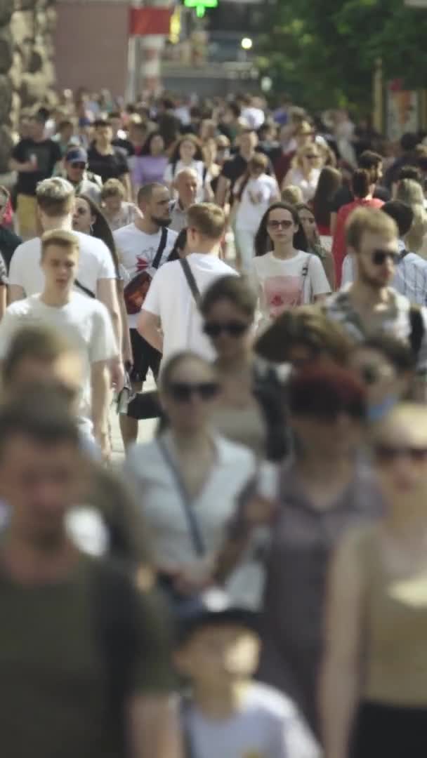 Verticale video van veel mensen die in een menigte langs een straat lopen — Stockvideo