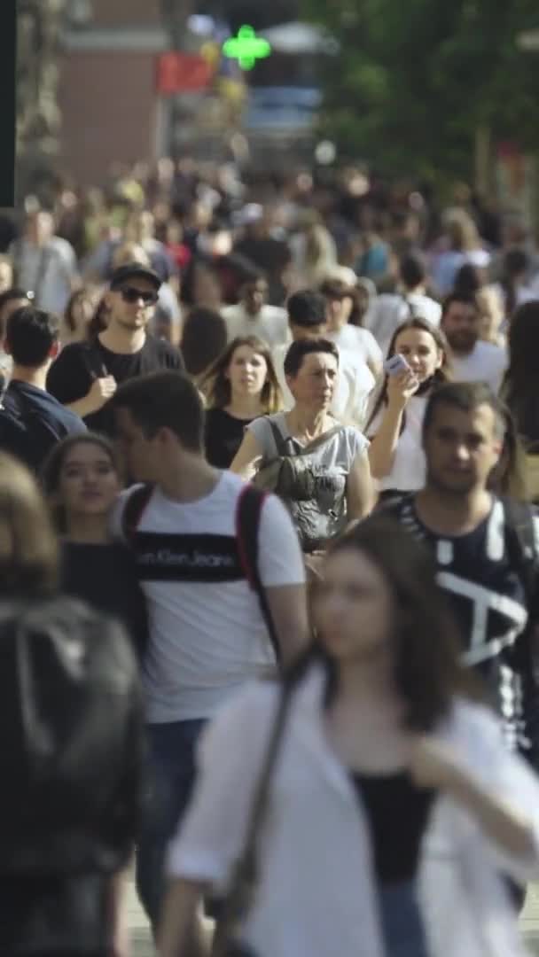 Vídeo vertical de muitas pessoas andando em uma multidão ao longo de uma rua da cidade — Vídeo de Stock